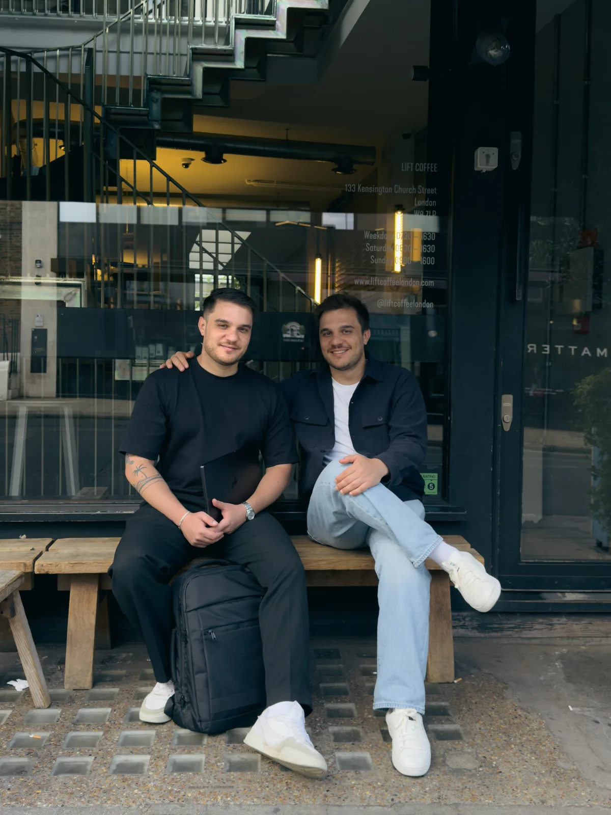 Bogdan and Dragos sitting on a bench outside a London café