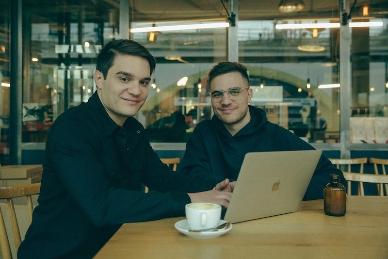 Bogdan and Dragos working on a laptop at a café